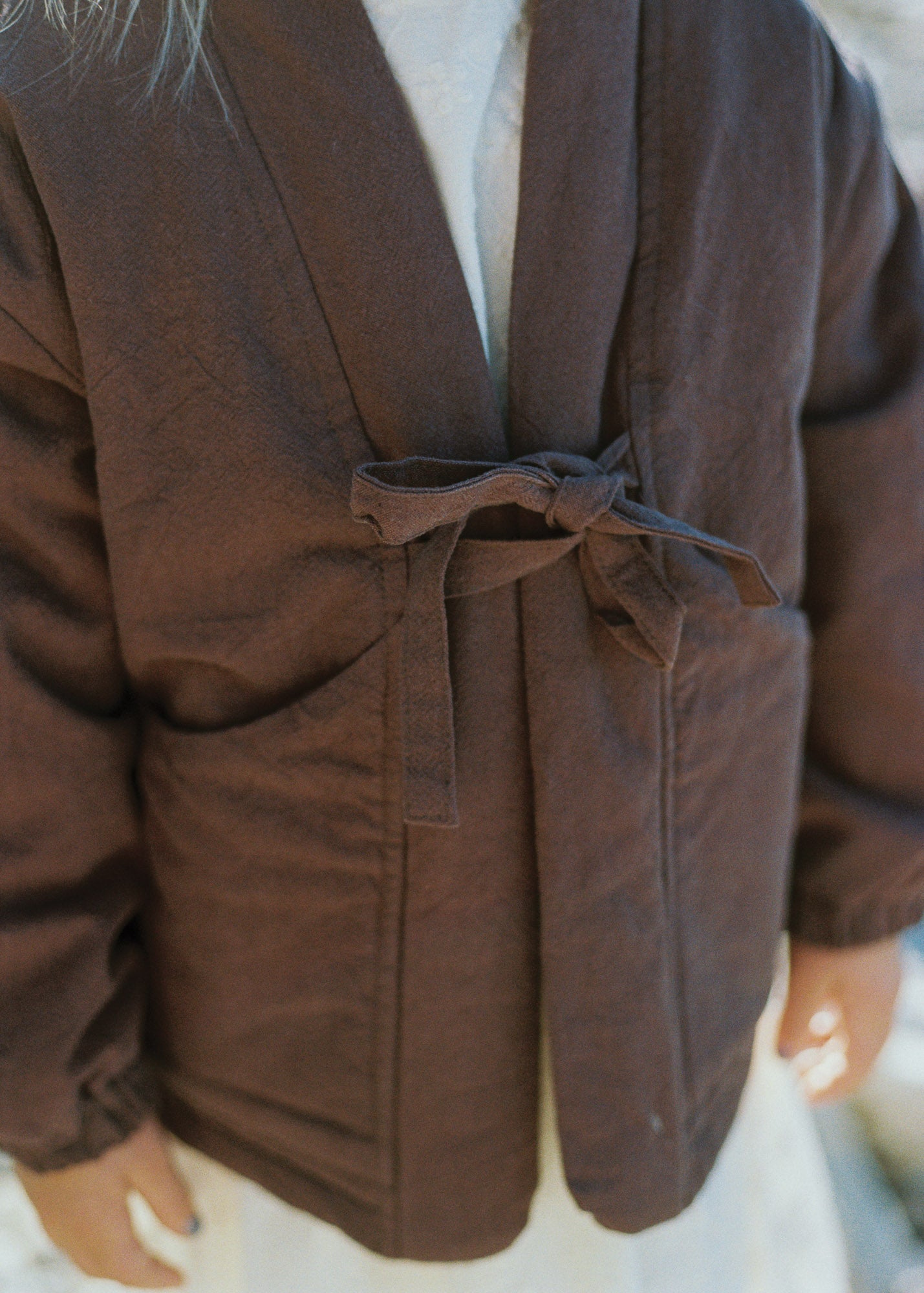Close-up of the Amélie Coat in Cacao brown, showing the front tie closure and large patch pockets.