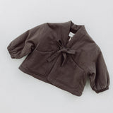 Amélie kids' coat in Cacao brown laid flat, showing the tie front, patch pockets and elasticated cuffs