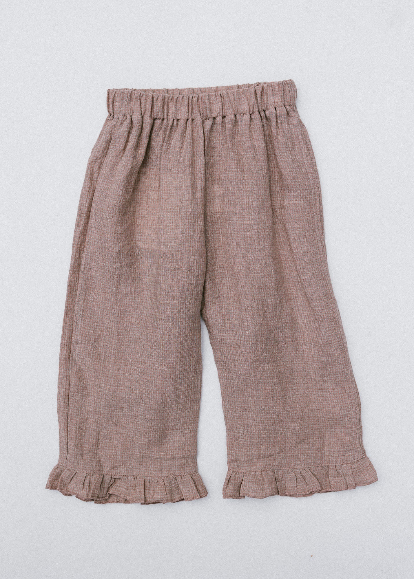 A pair of toddler's wide-leg linen pants in a dusty rose-brown color, featuring an elastic waistband and ruffled hems, laid flat against a light gray background.